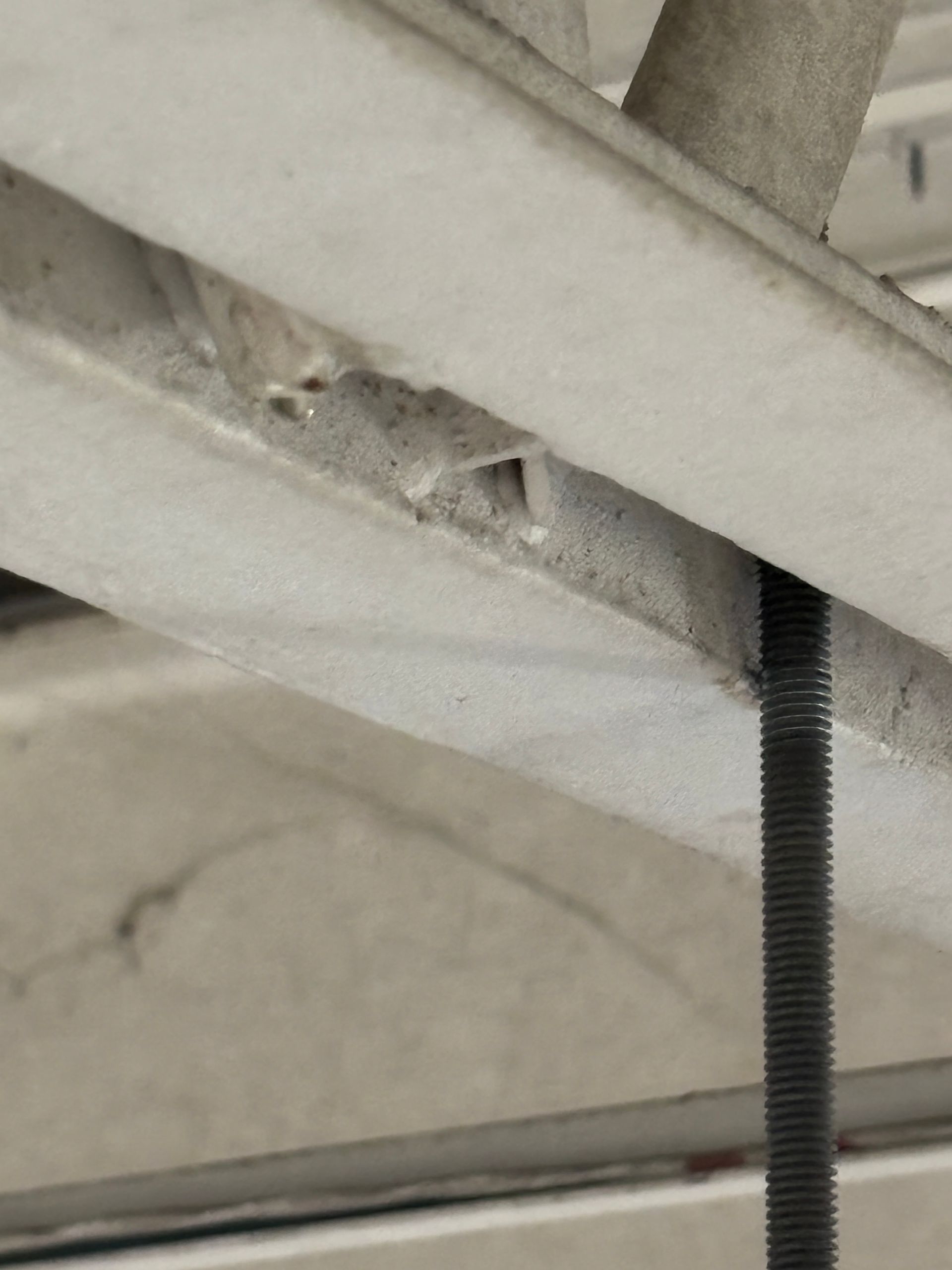 Close-up of a concrete ceiling structure with a threaded rod support.