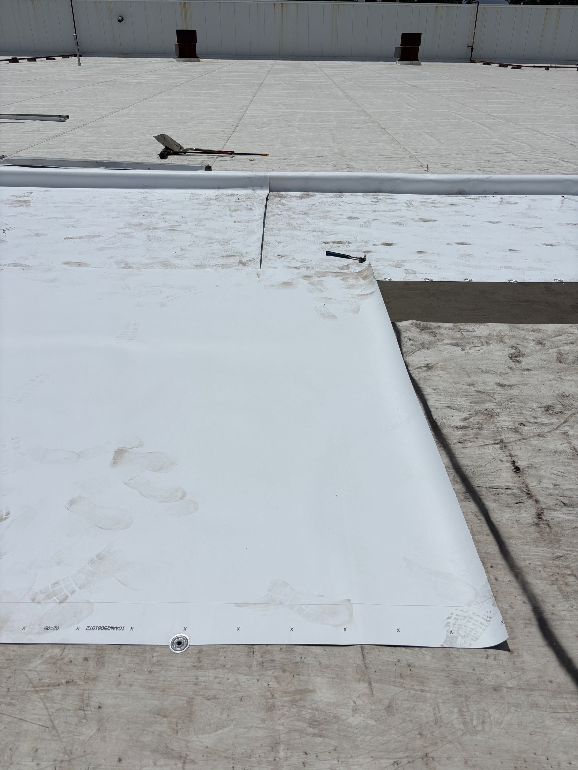 White roof with overlapping membrane sections, showing seams and exposed edge.