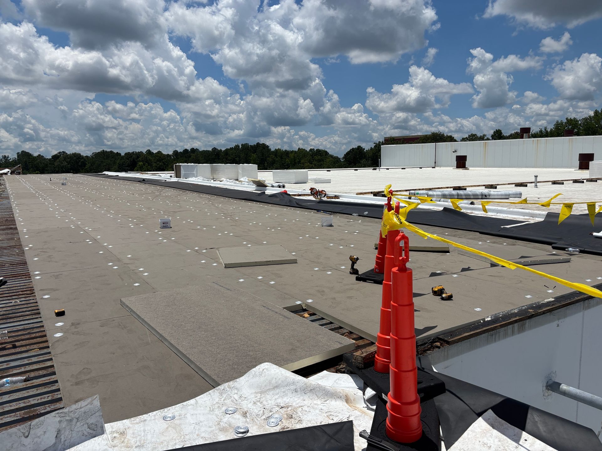 Rooftop with safety cones and yellow rope, under a cloudy sky.