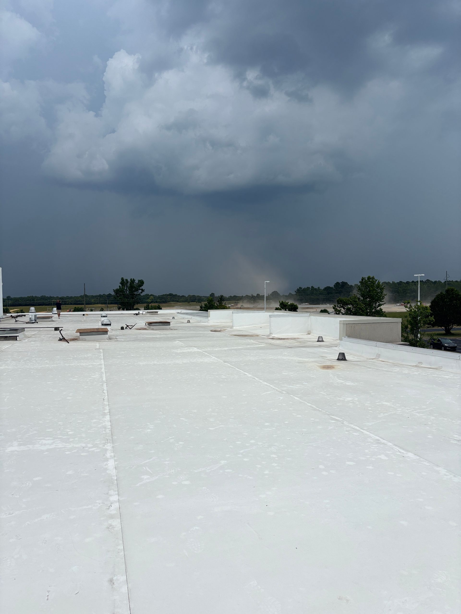 Overcast sky over a flat white roof with a distant storm and a hint of rain.
