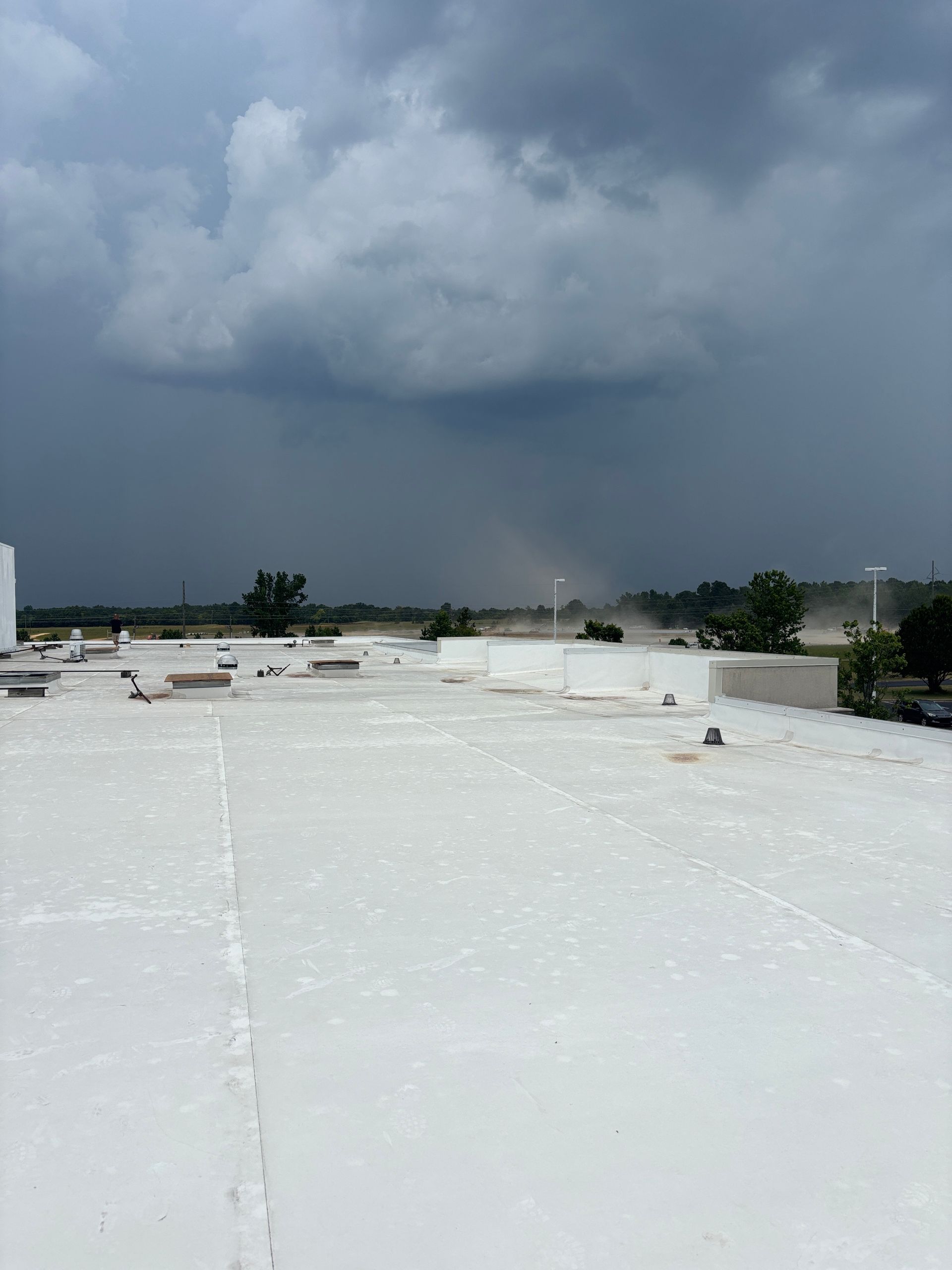 Overcast sky above a white roof. Rain visible in the distance.