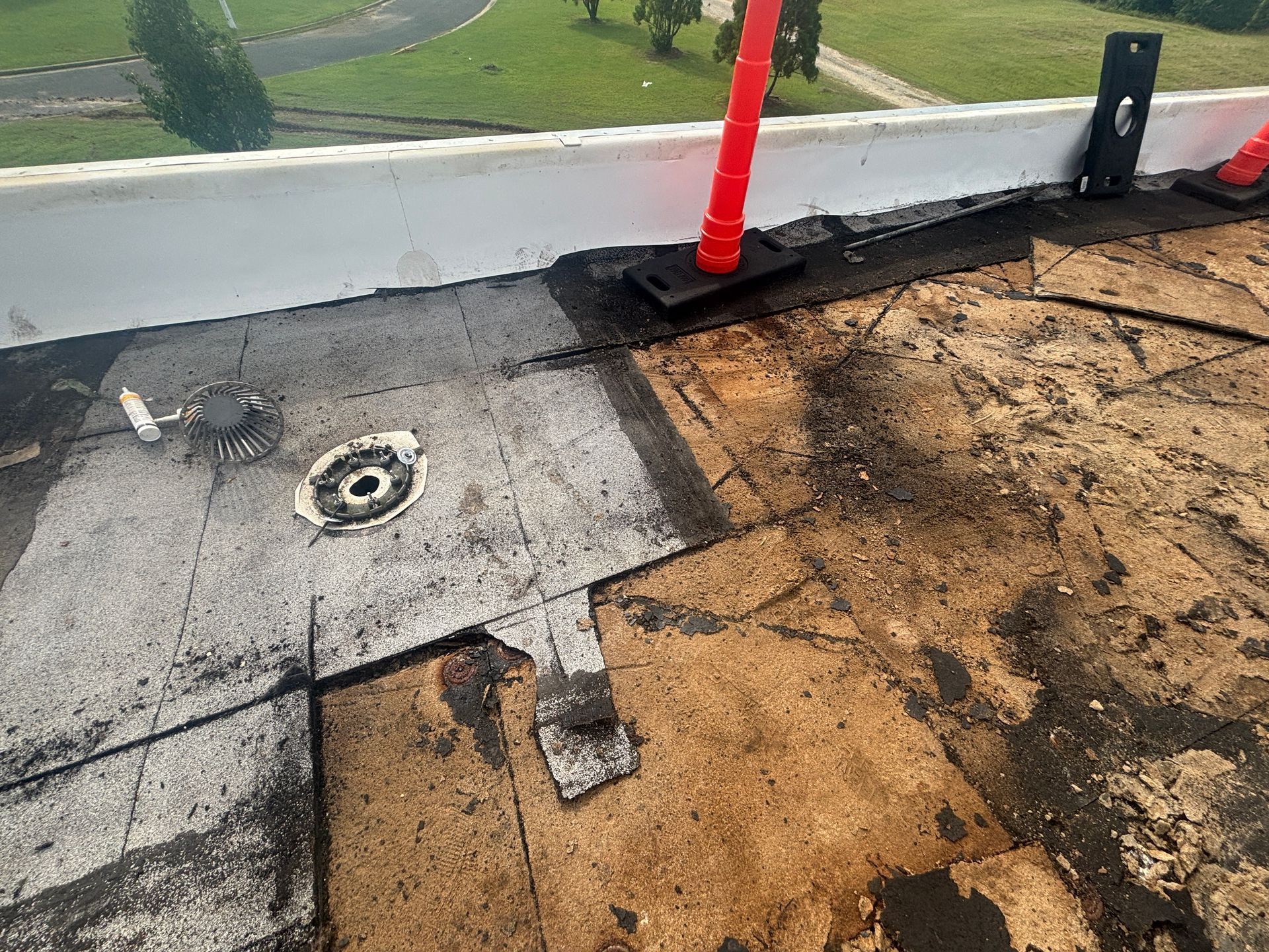 Damaged flat roof with drain and red safety poles.