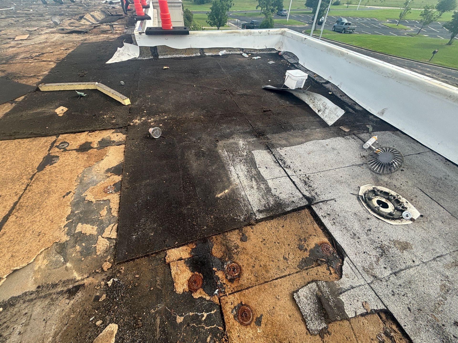 Damaged commercial flat roof with exposed layers, debris, and a drain.
