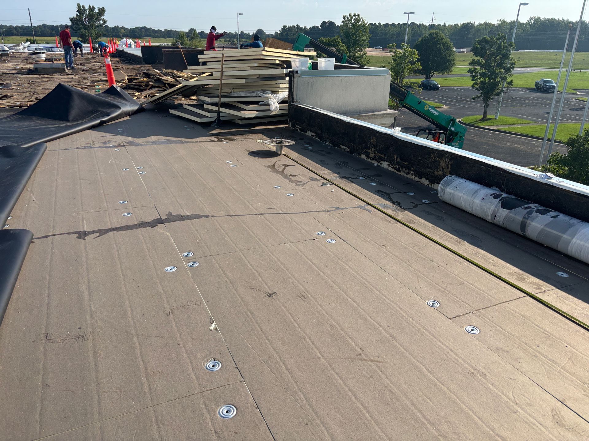 Roof construction with materials and workers visible.