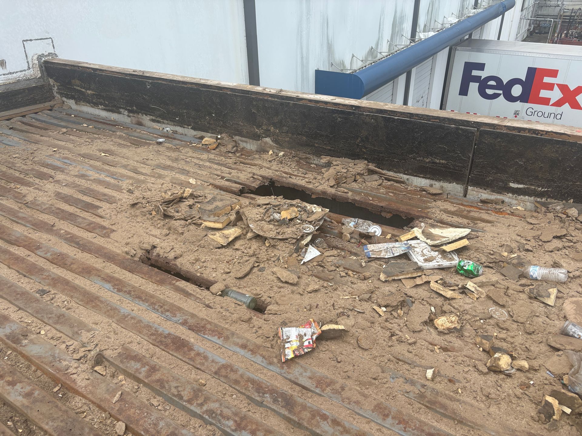 Dirty truck bed filled with debris and trash; a FedEx sign visible in the background.