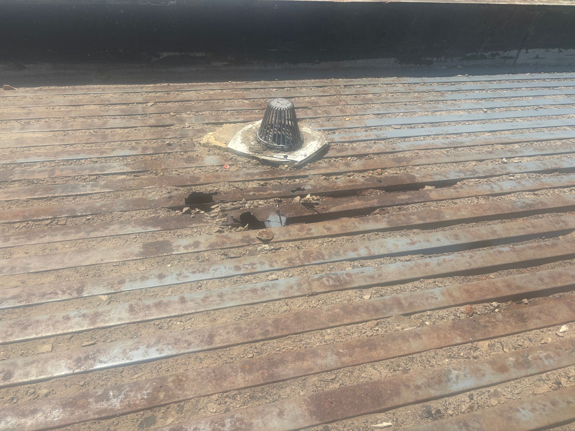 Rusty metal surface with central hitch and damaged areas.