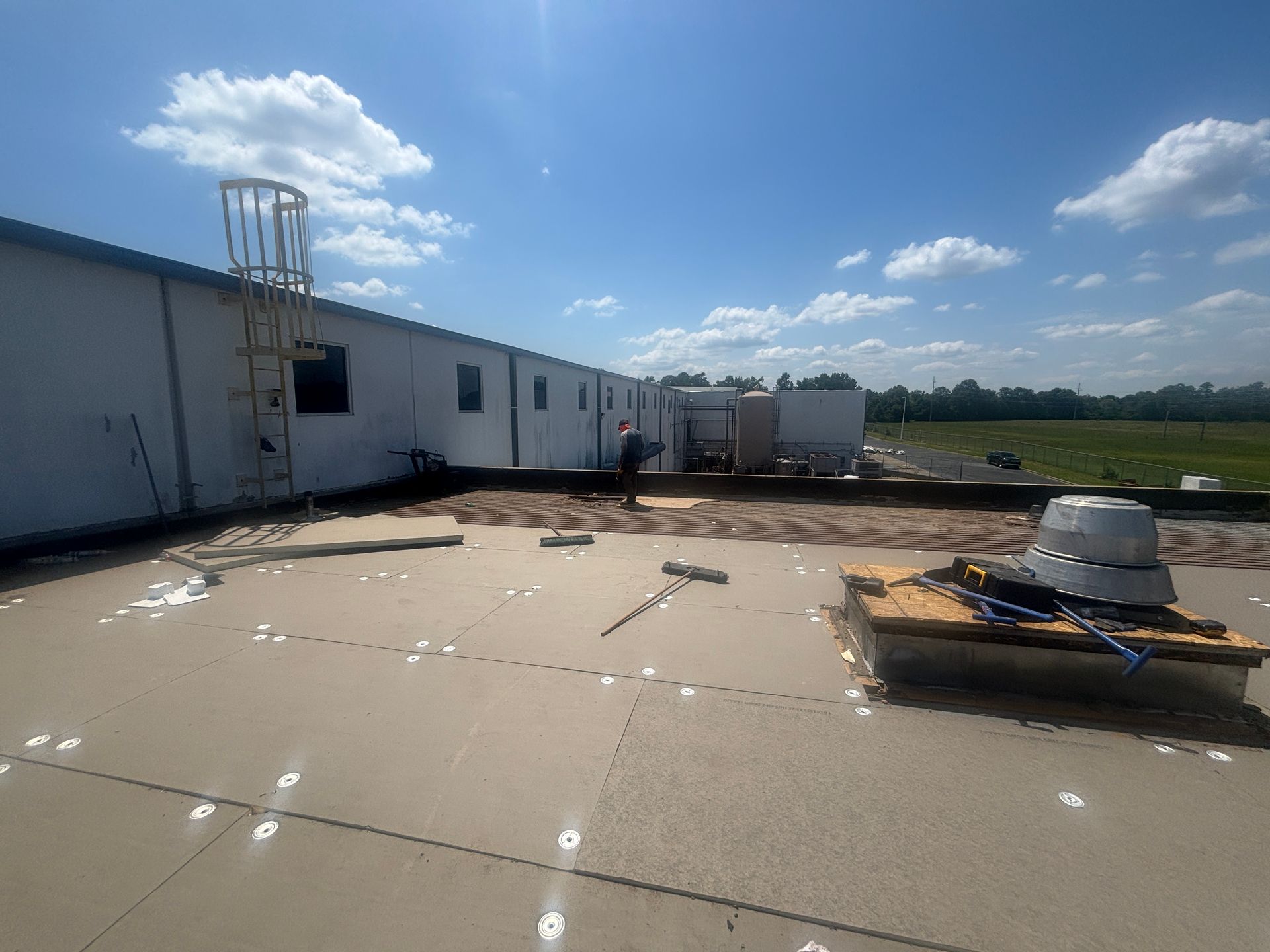 Workers on a flat roof under a blue sky, performing construction.