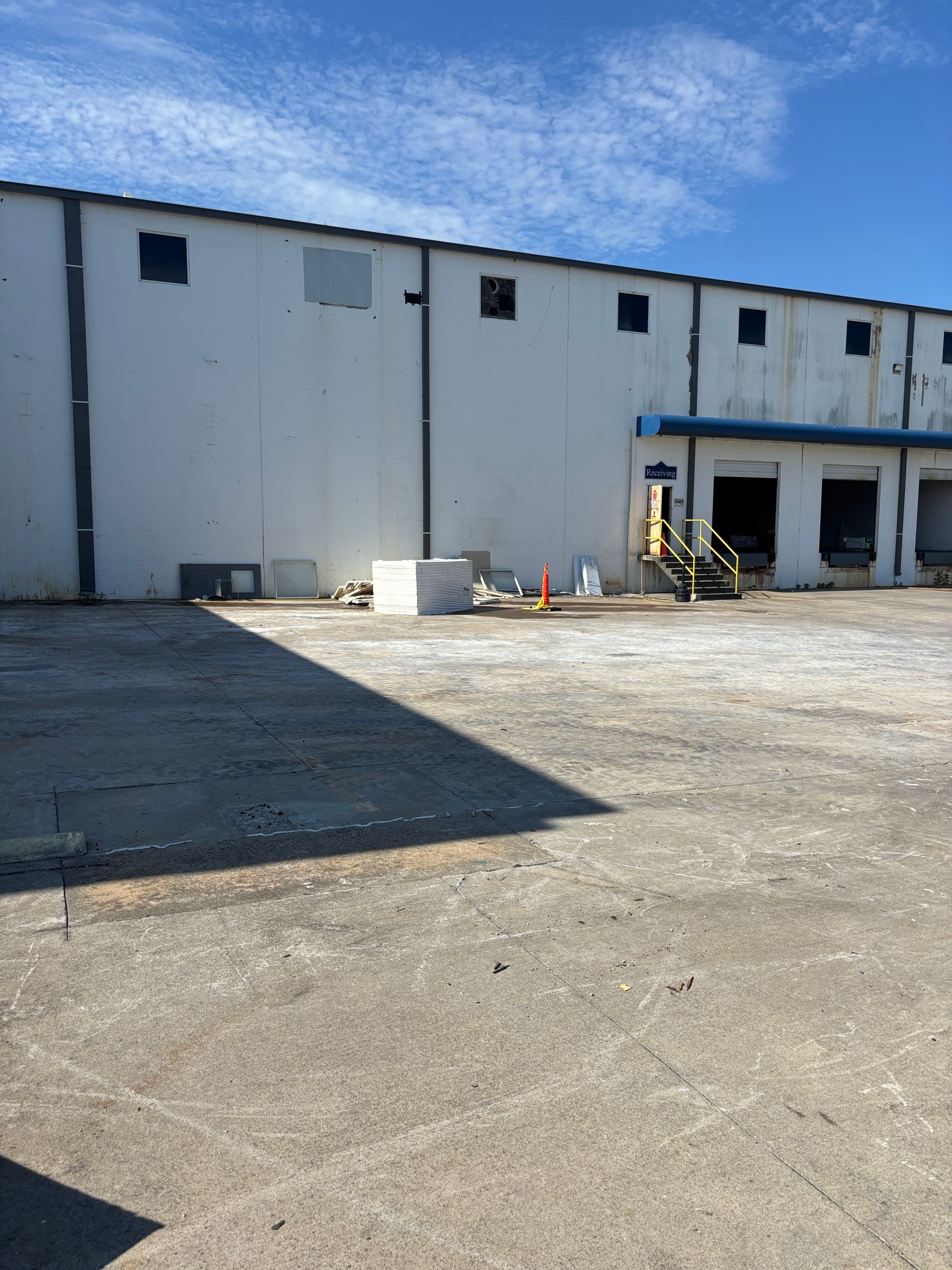Warehouse exterior with loading docks, cloudy sky.