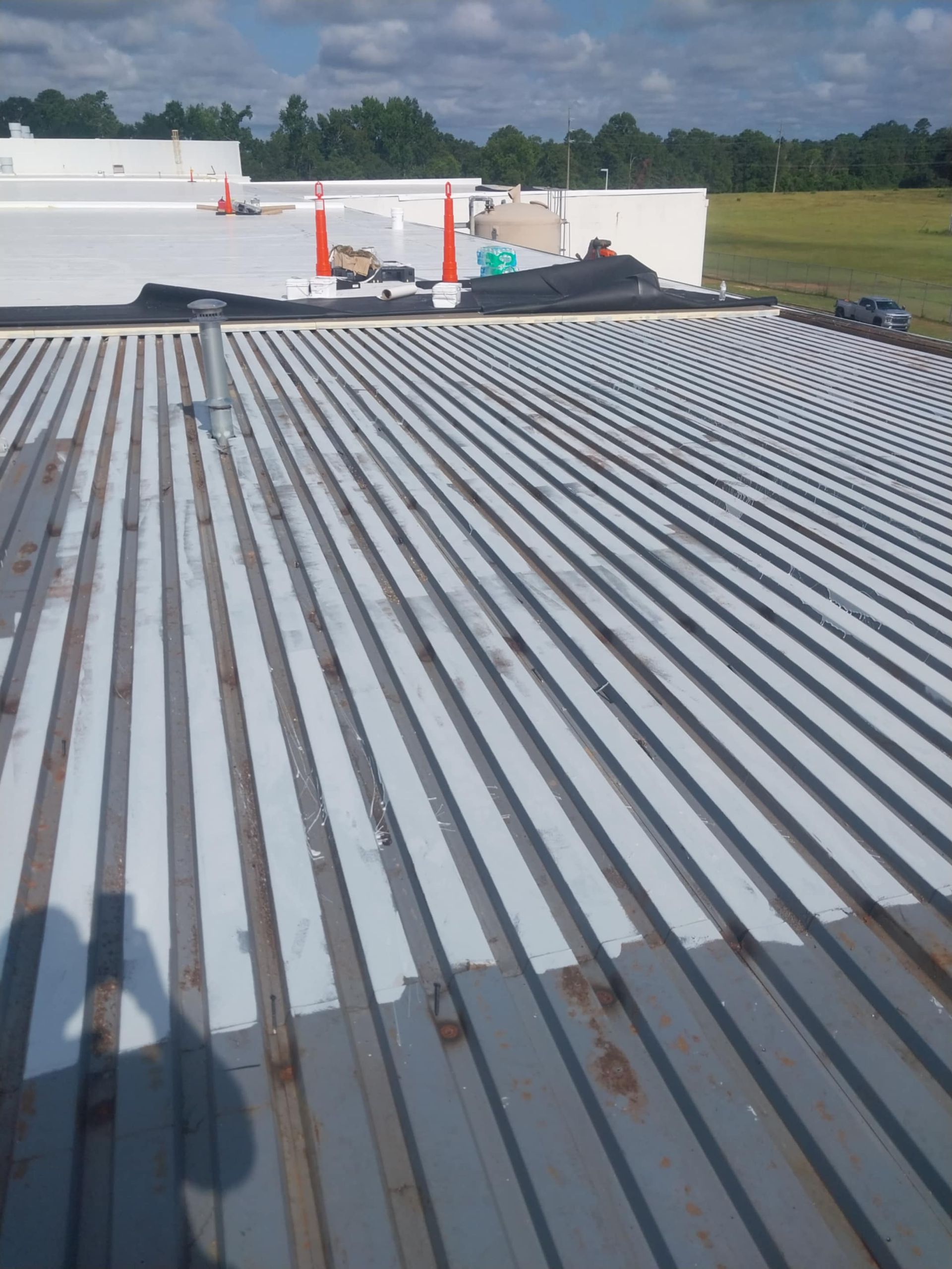 Overhead view of a corrugated metal roof with white stripes and light blue sky in the background.