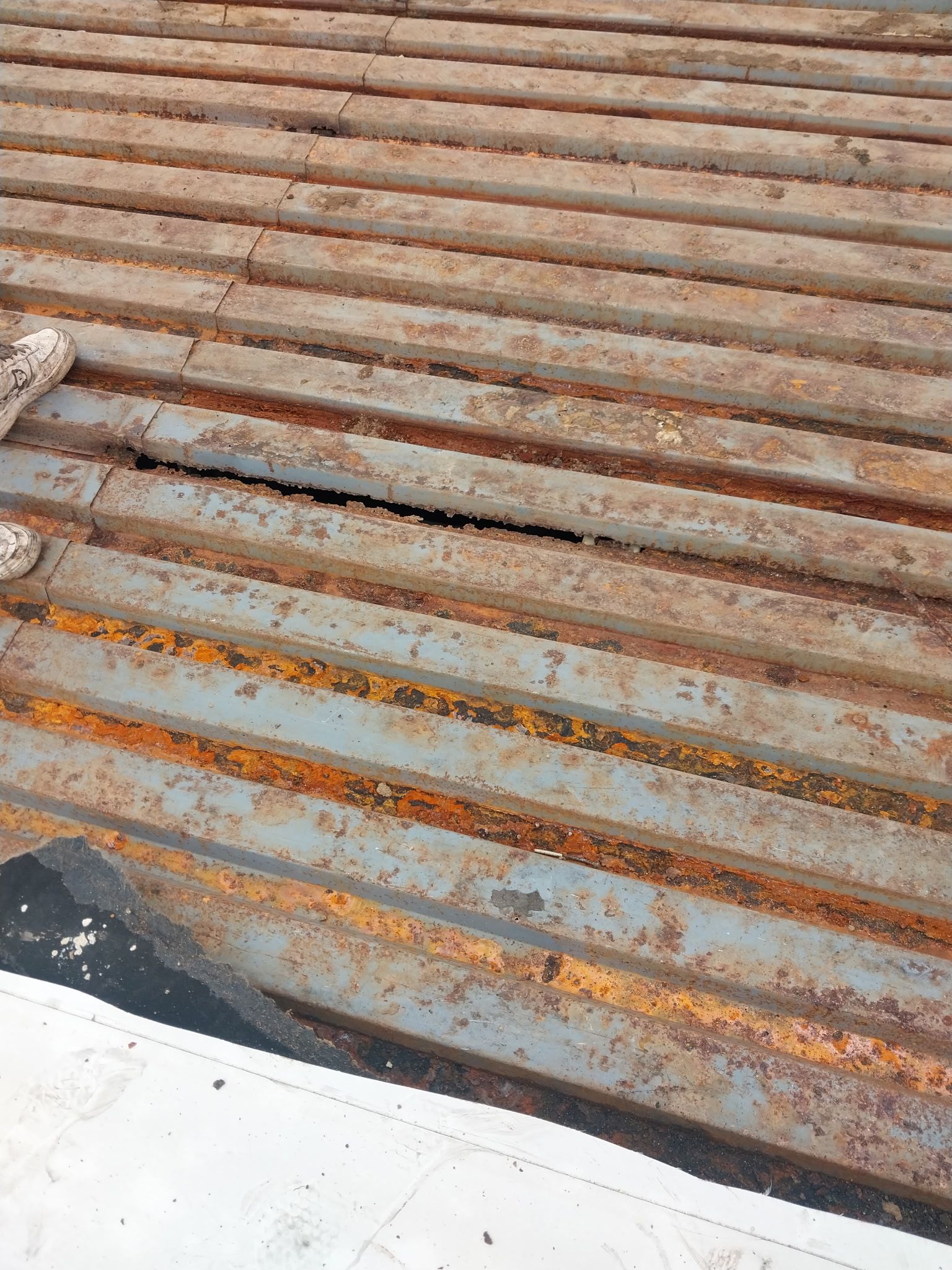 Rusty metal surface with a dark crack running through it, possibly a roof.