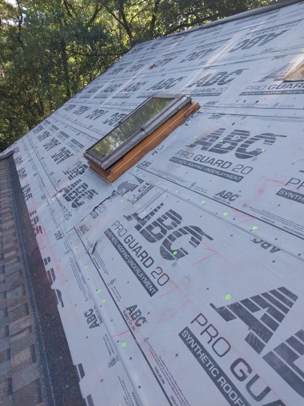 Rooftop with skylight, covered in synthetic underlayment, ready for shingle installation.