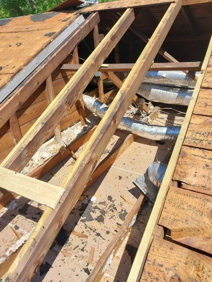 Roof construction: damaged wooden beams with visible ductwork, part of a home's structure.