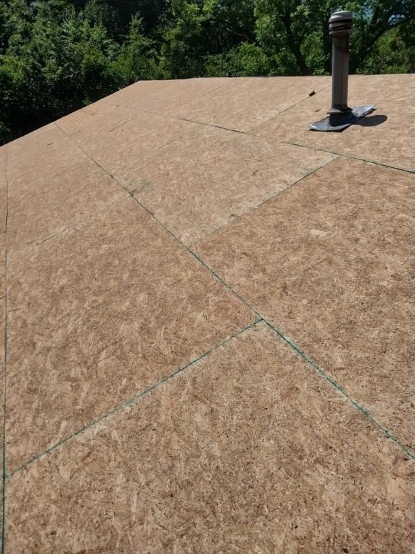 OSB sheathing on a roof with a metal vent pipe. Green marking lines are visible.