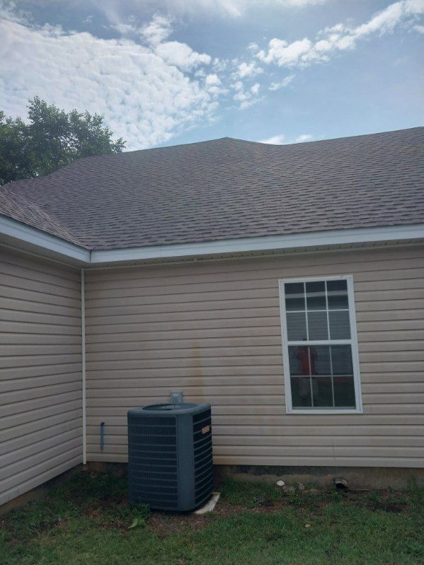 Beige house exterior with tan siding, roof, and AC unit.  Blue sky with clouds.