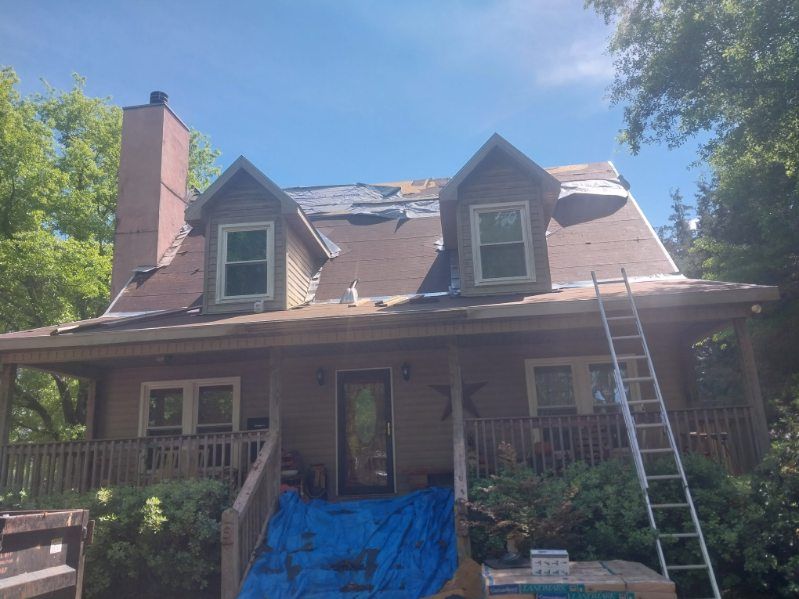 House with partially removed roof, construction in progress; ladder leans against the side.