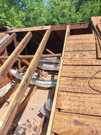 View of wooden roof supports with exposed ductwork, partially dismantled.