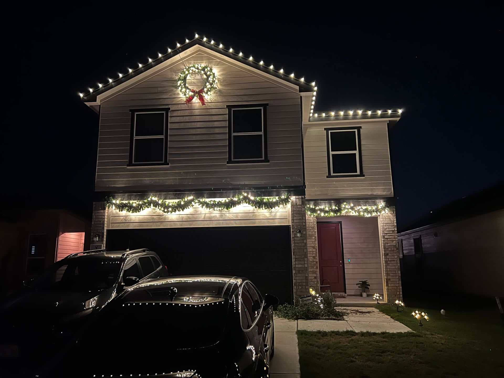 House decorated for Christmas with lights and wreath at night.