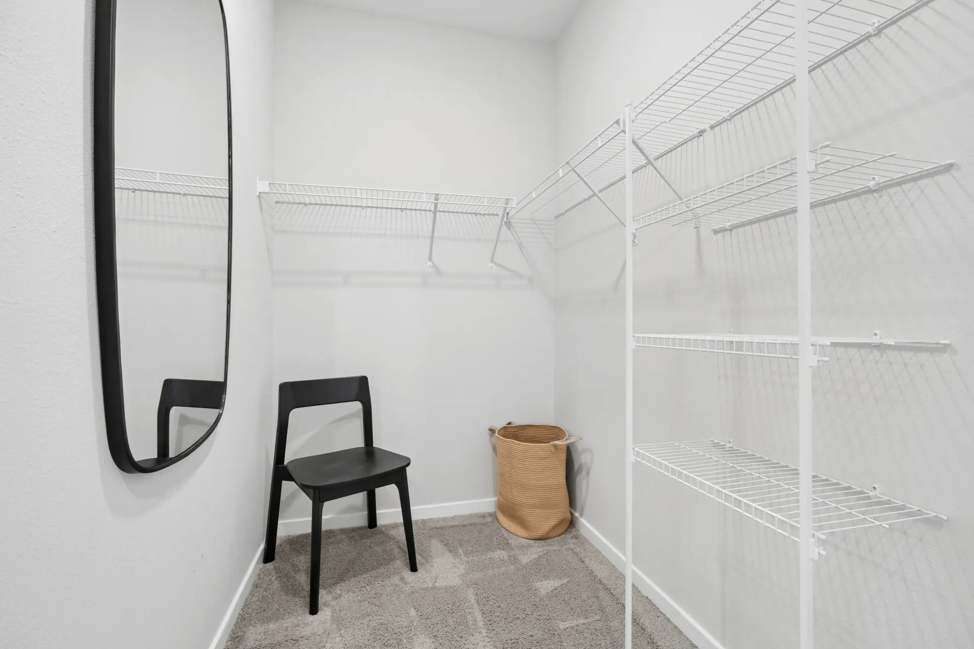 Walk-in closet with shelves, a chair, a mirror, and a basket.