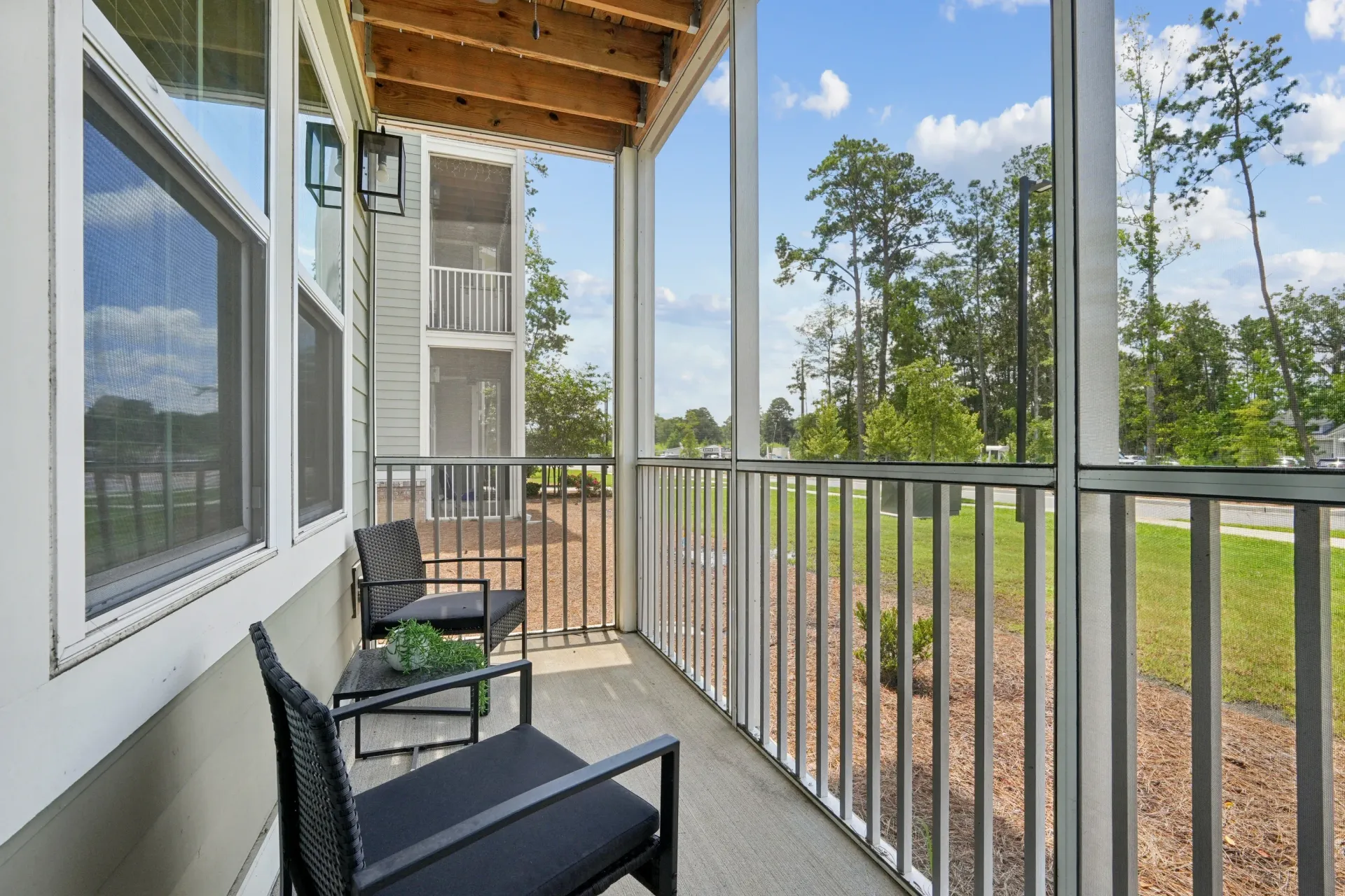 Screened-in balcony with two chairs and a small table.