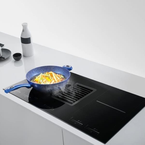 Een pan met voedsel kookt op een zwarte inductiekookplaat Bora