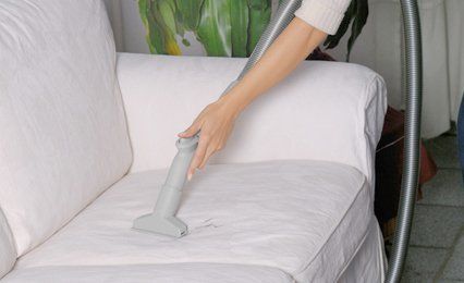 A white sofa being vacuumed