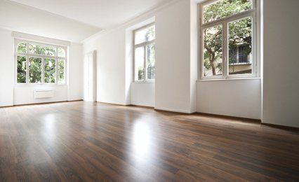 An empty white room with a polished wooden floor