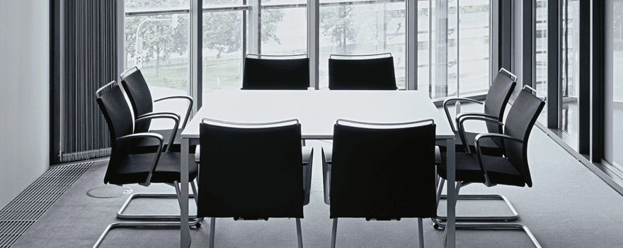 A meeting table and black chairs in a window recess