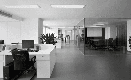 Open plan office with white desks, black chairs and dark grey vinyl floor