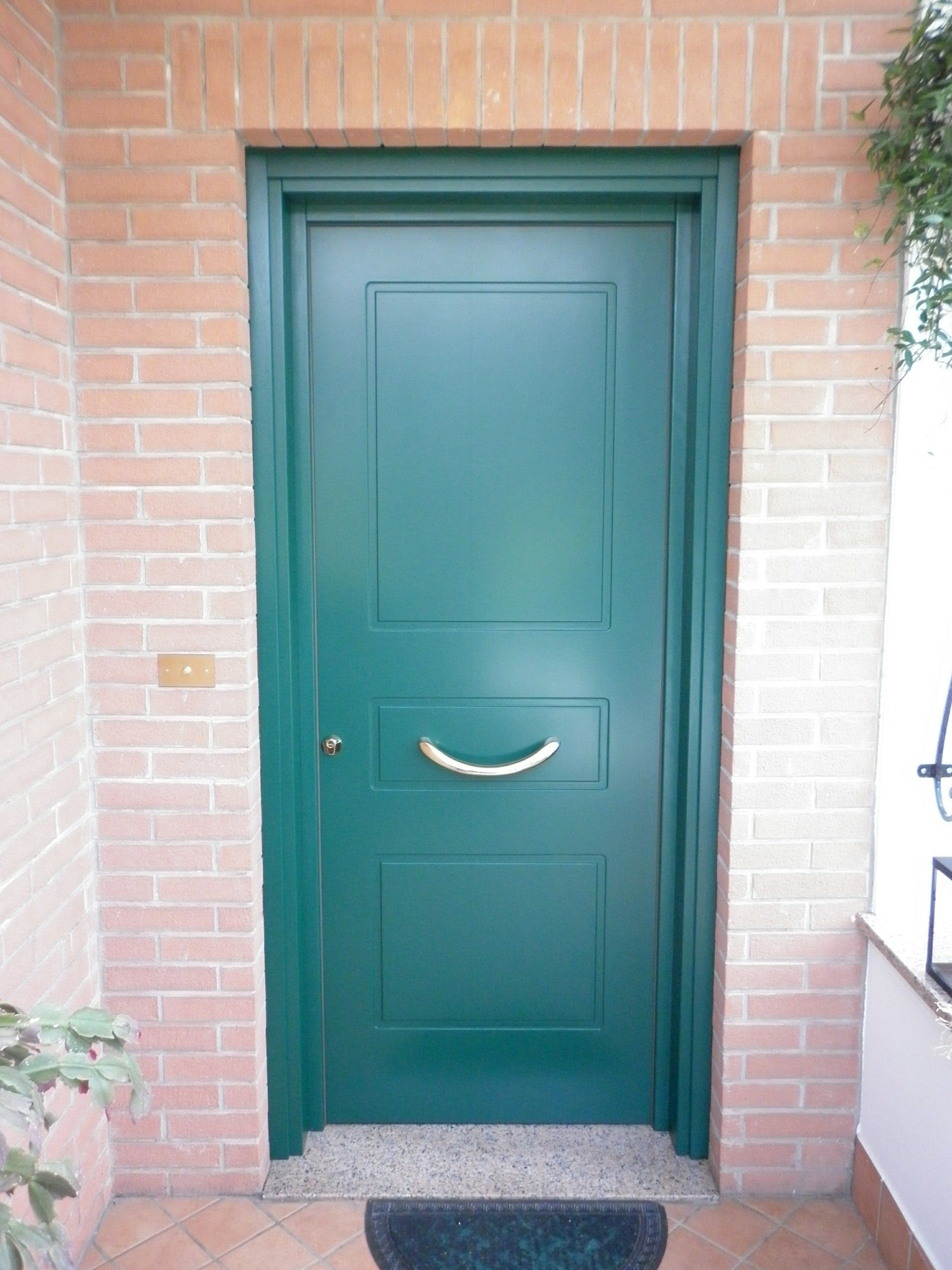 Una porta verde è contro un muro di mattoni