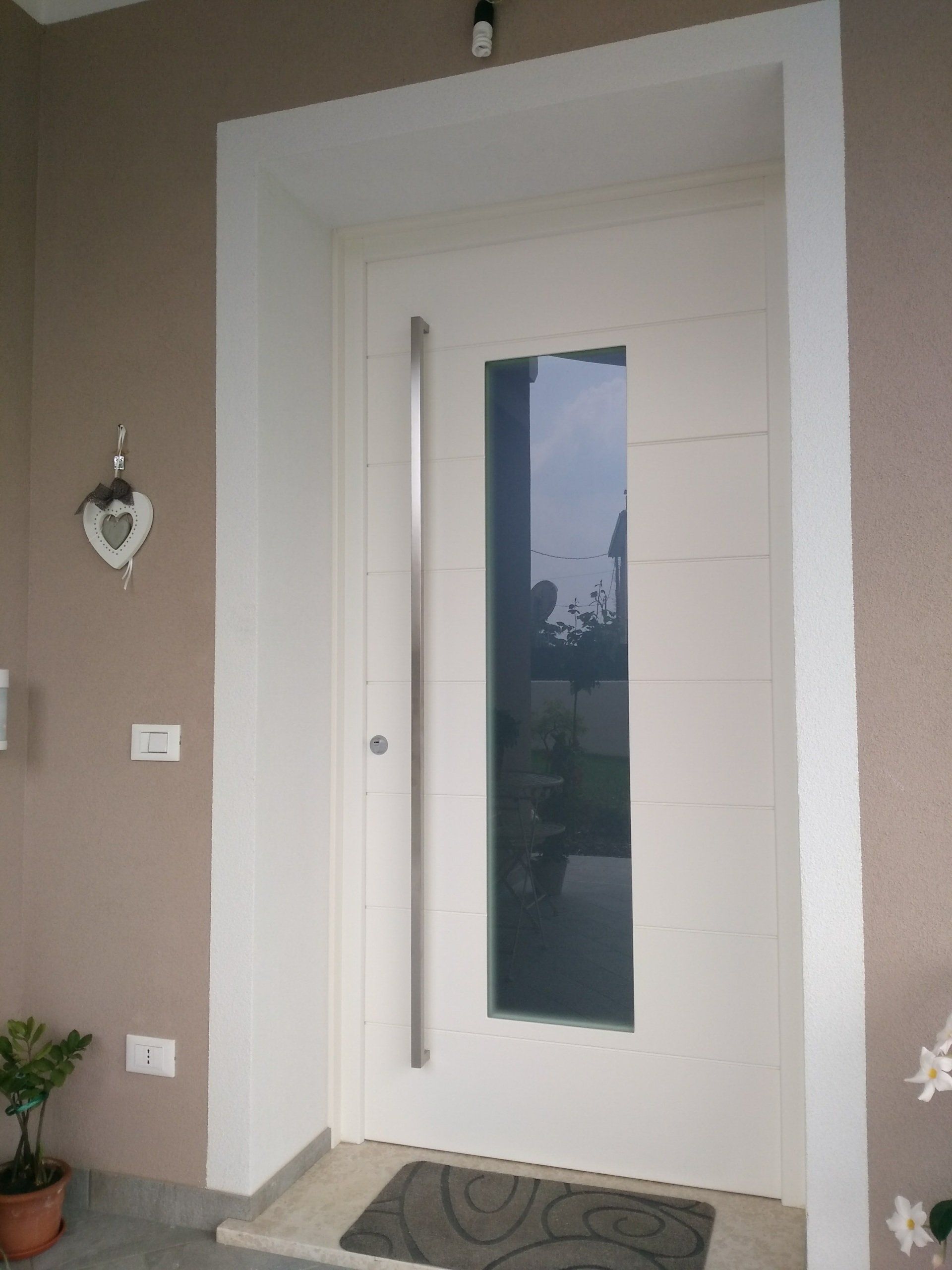 Una porta bianca con una finestra di vetro e un cuore sul muro