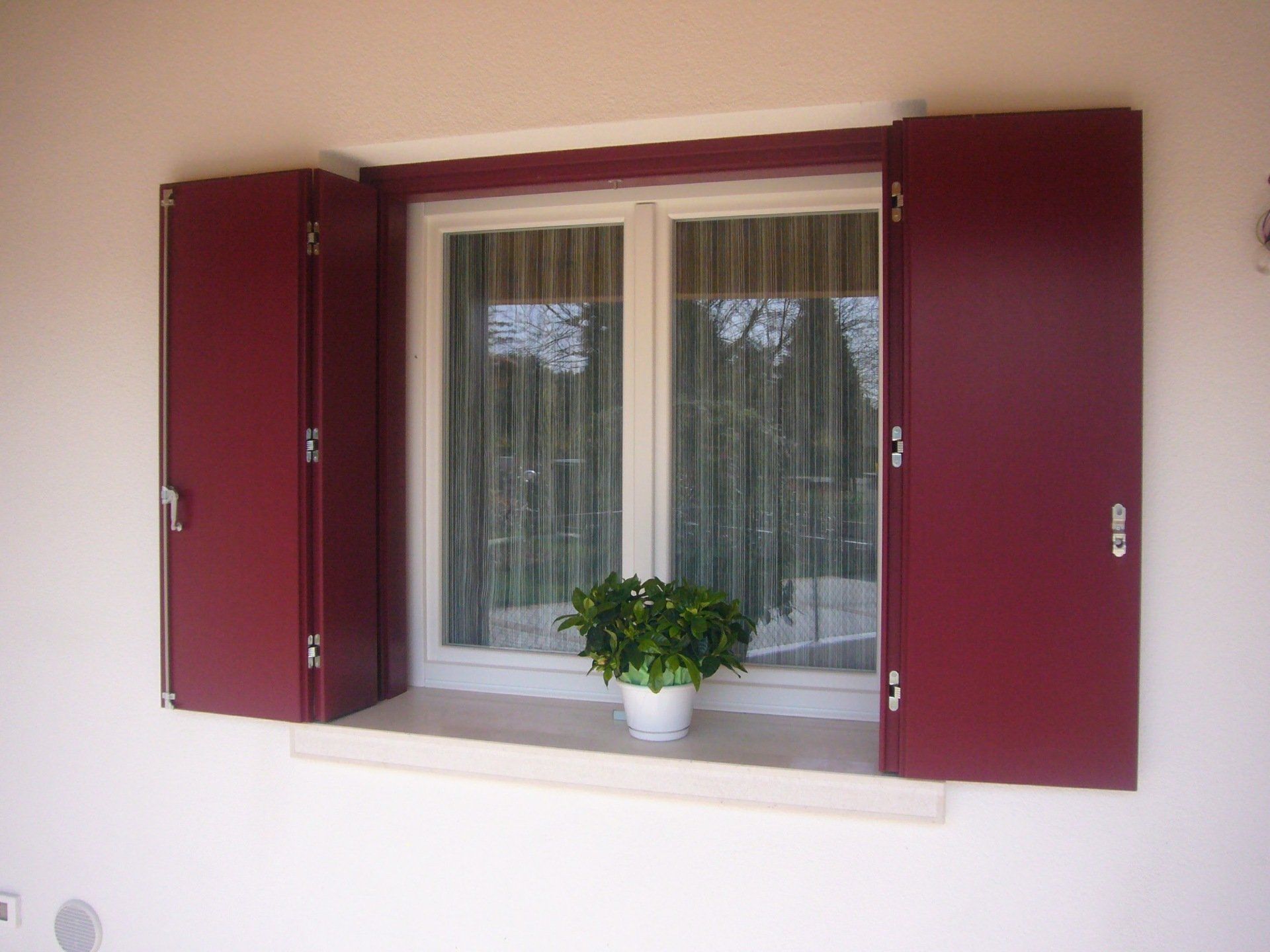 Una finestra con le persiane rosse e profili in legno