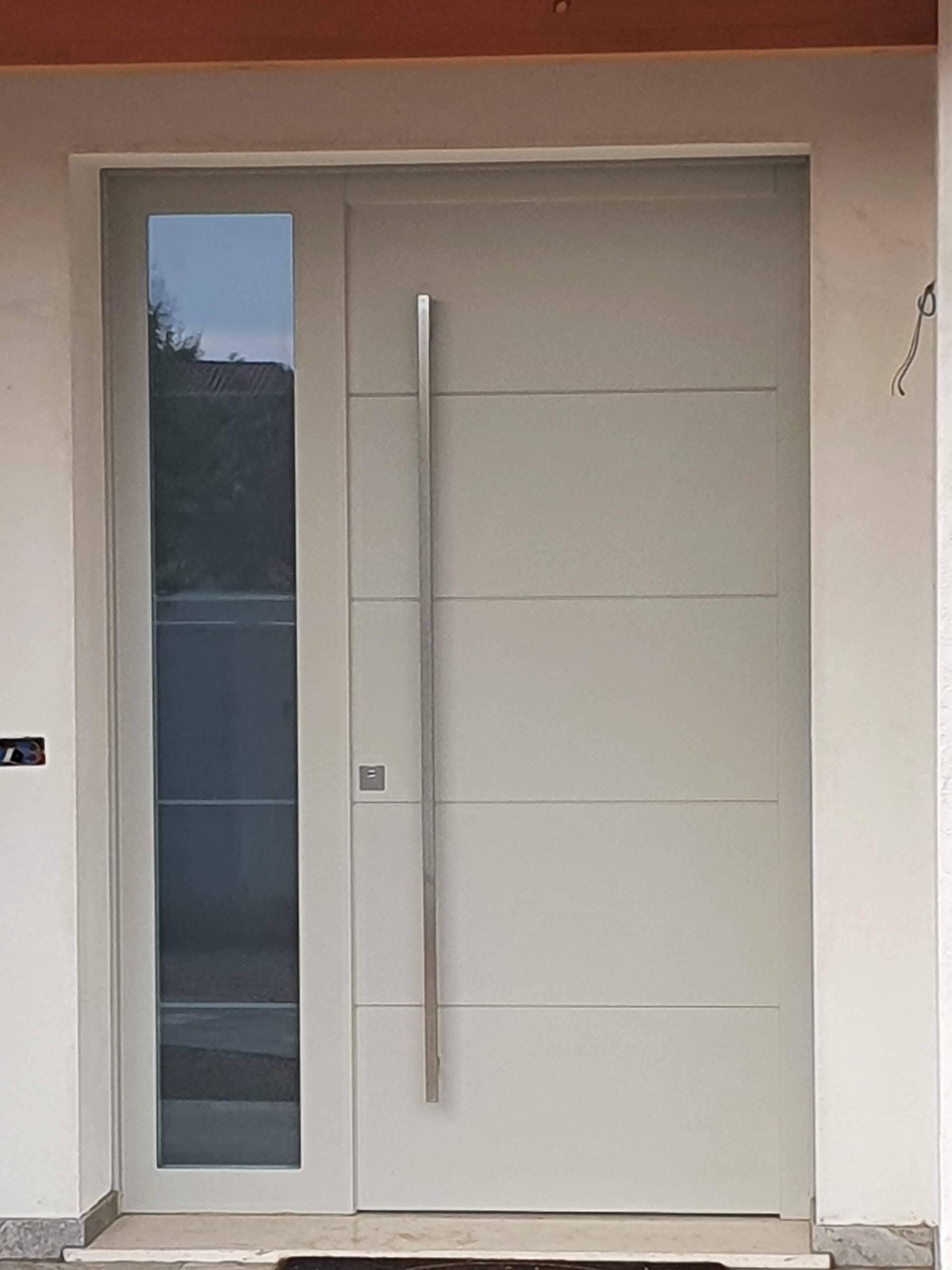 Una porta bianca con maniglia in acciaio inox e una finestra in vetro.