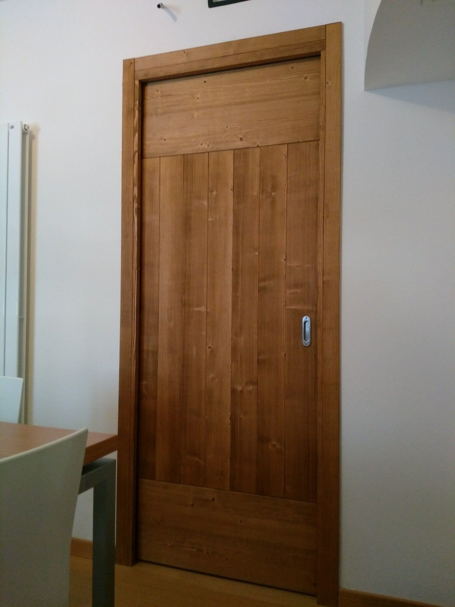 Una porta di legno in una stanza con un tavolo e delle sedie