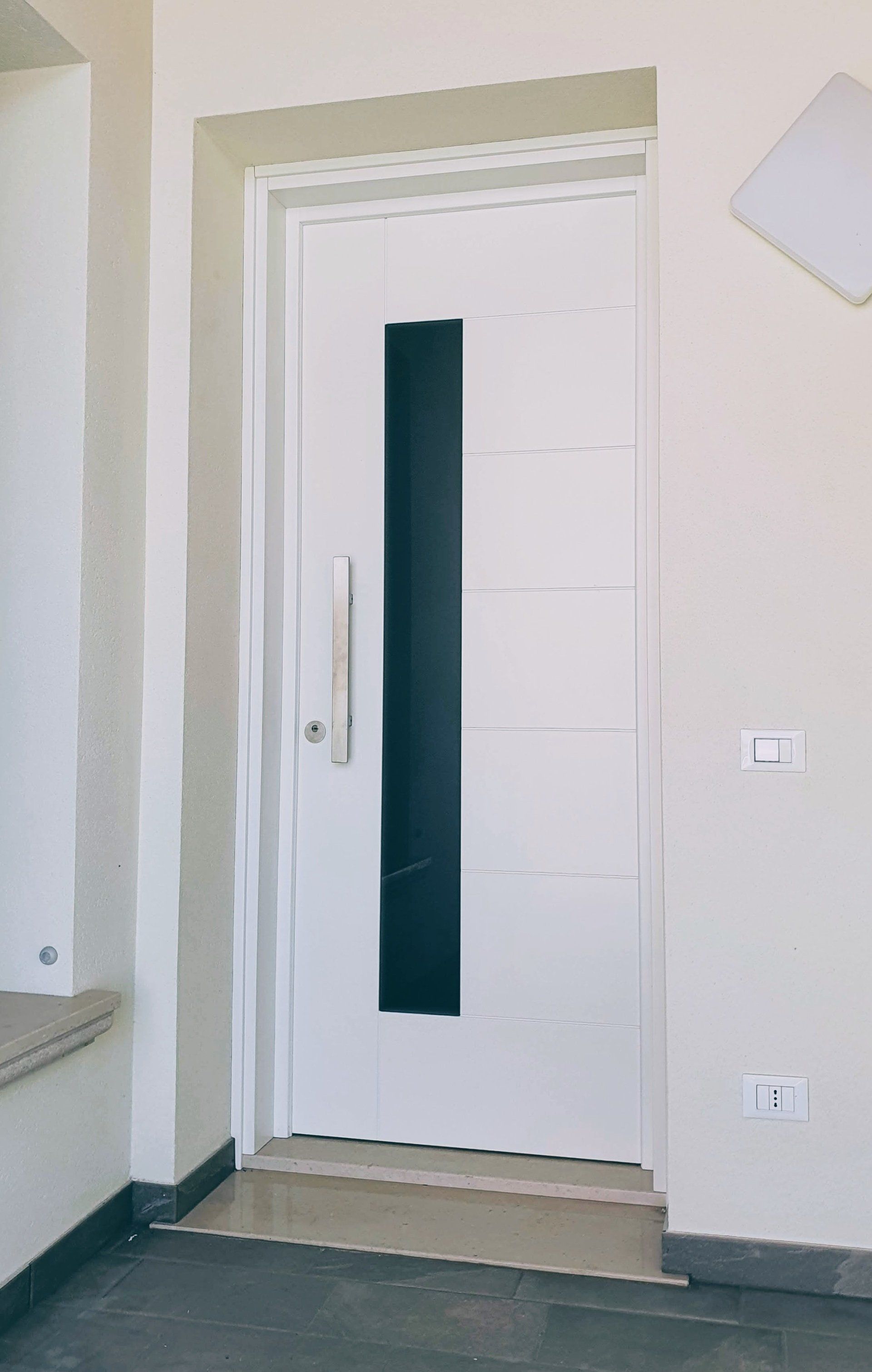 Una porta bianca con una finestra nera in una stanza