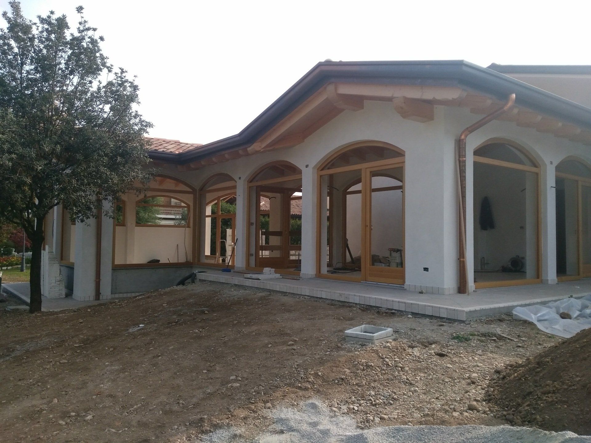 Una casa bianca con finestre ad arco e un albero di fronte