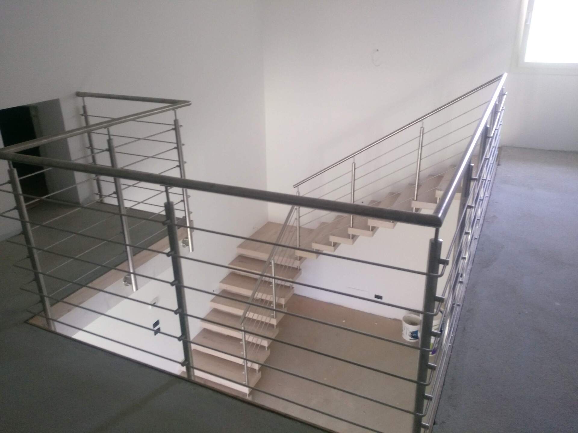 Una scala con ringhiera in acciaio inox in una stanza