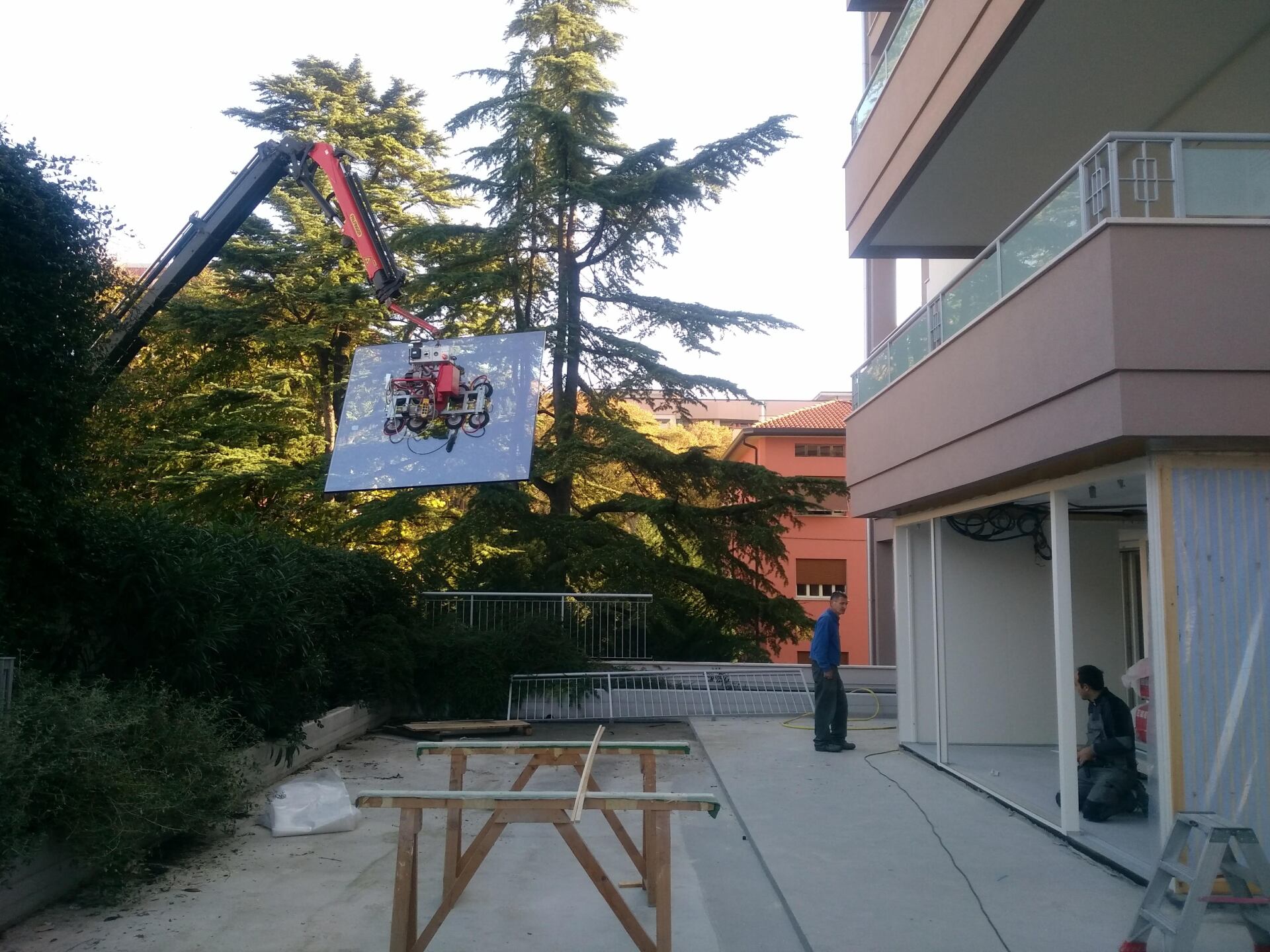 Una gru sta sollevando un grande pezzo di vetro davanti a un edificio