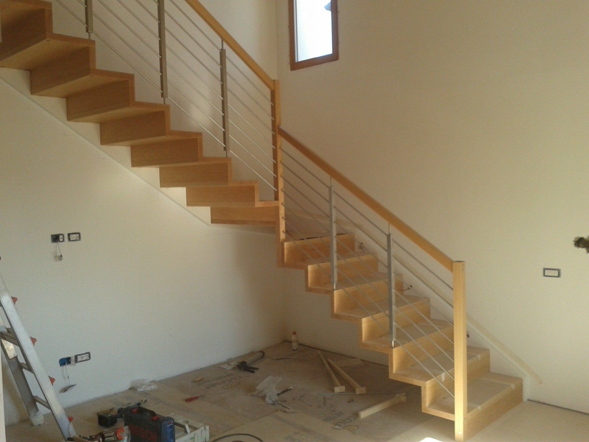 Una scala di legno con una ringhiera di metallo in una stanza