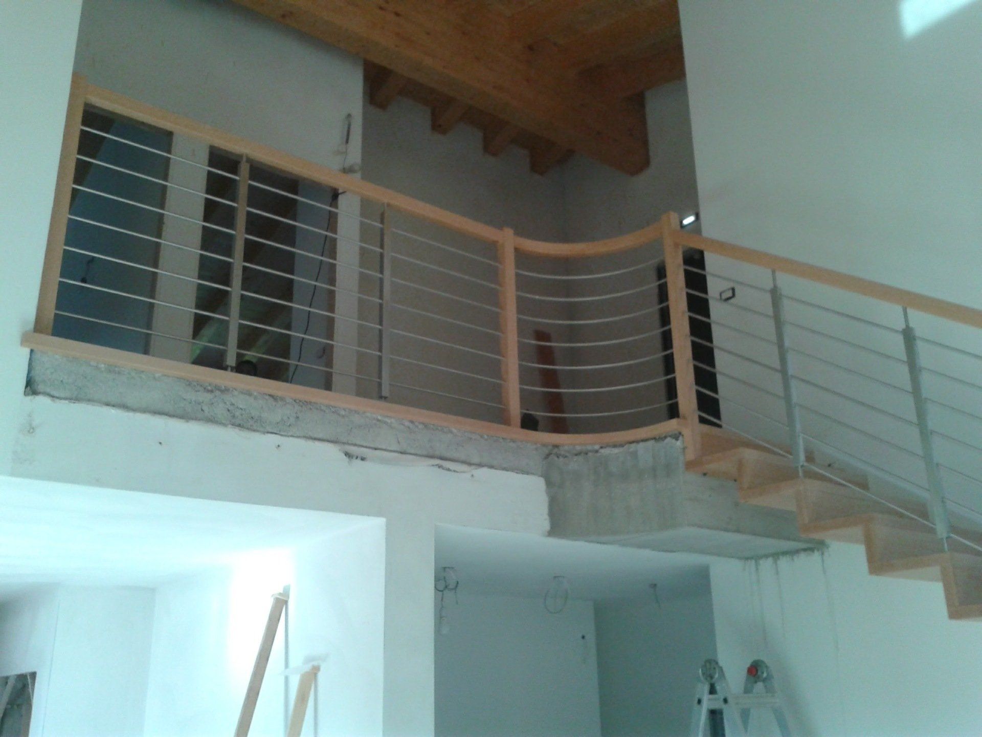 Una scala con una ringhiera in legno e una scala sullo sfondo