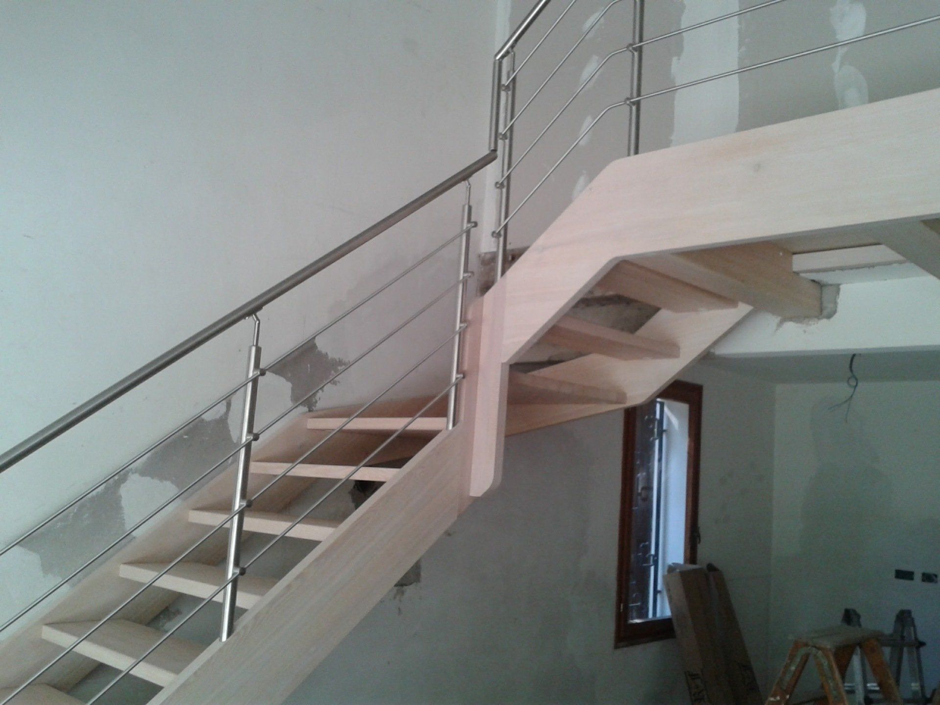 Una scala in legno con ringhiera in acciaio inox