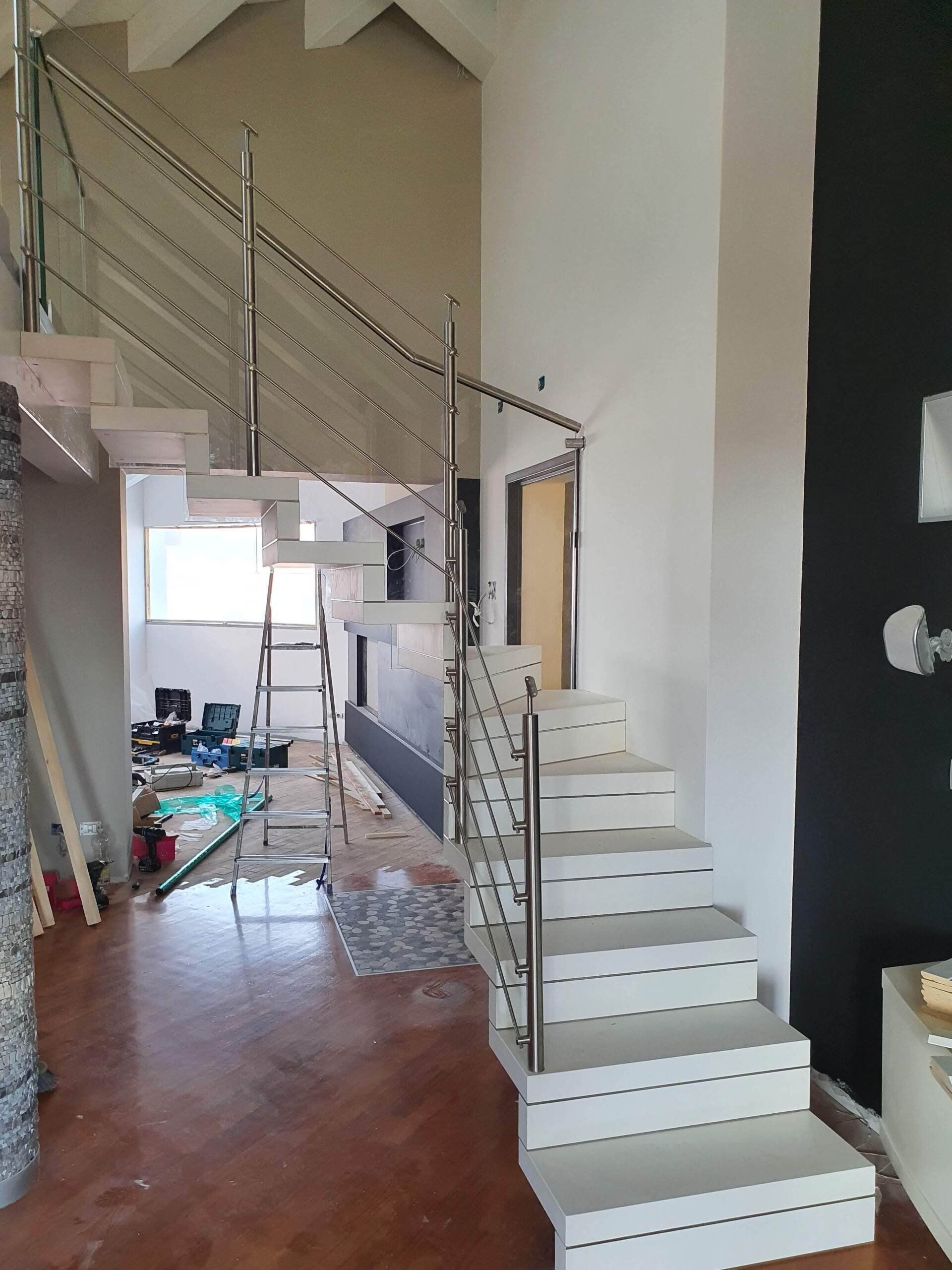 Una scala bianca con una ringhiera in acciaio inossidabile in una stanza.