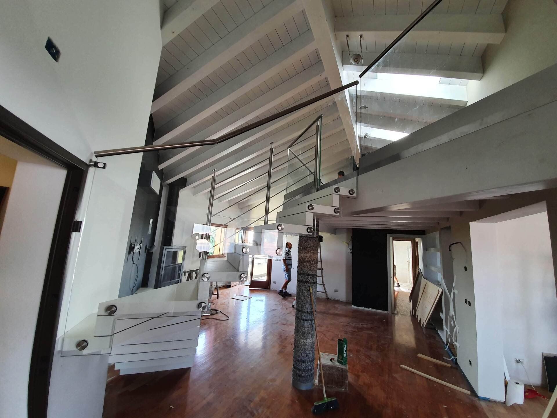 Una grande stanza con una scala e un pavimento in legno