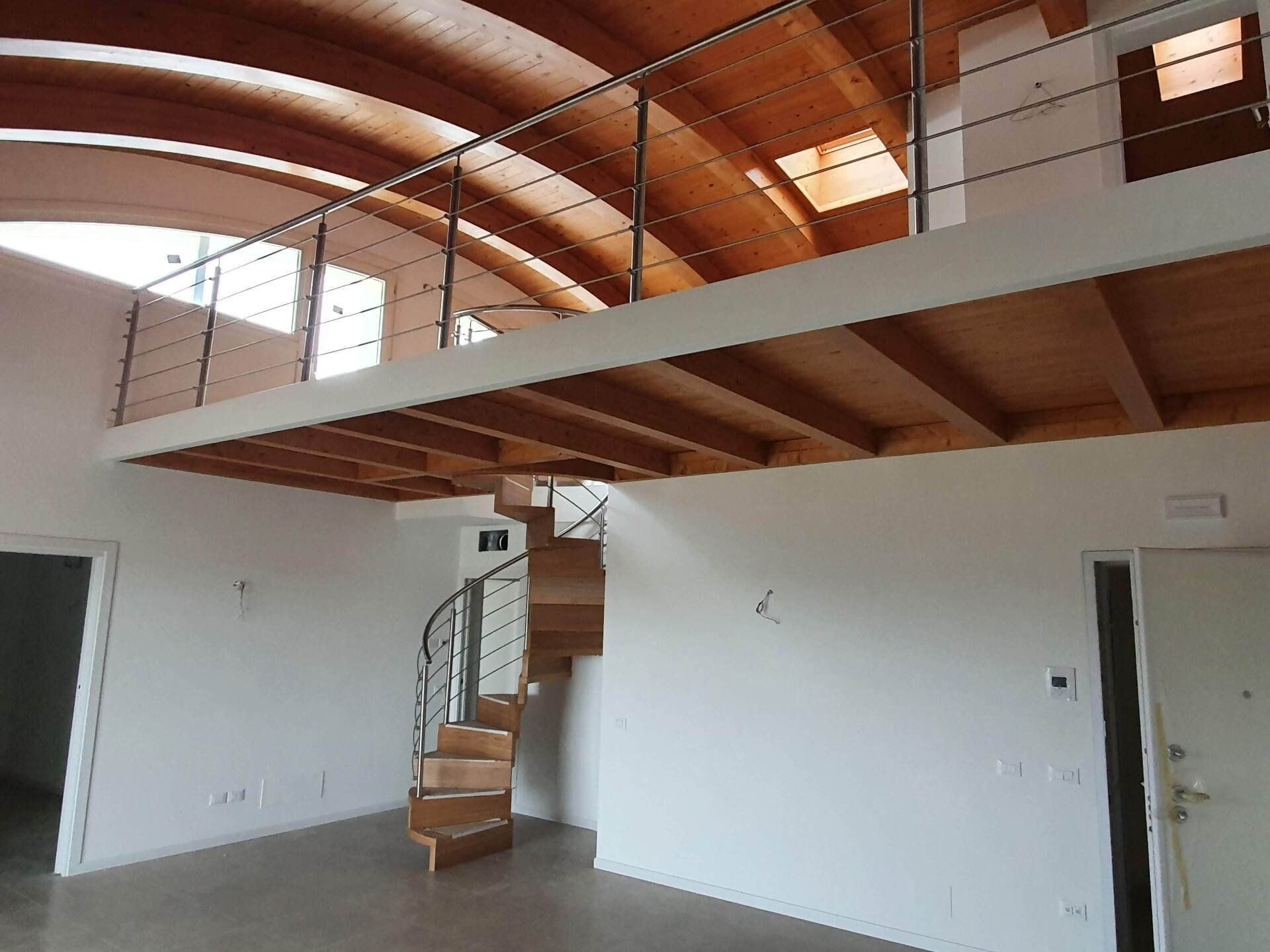 Una stanza vuota con una scala a chiocciola che conduce al secondo piano