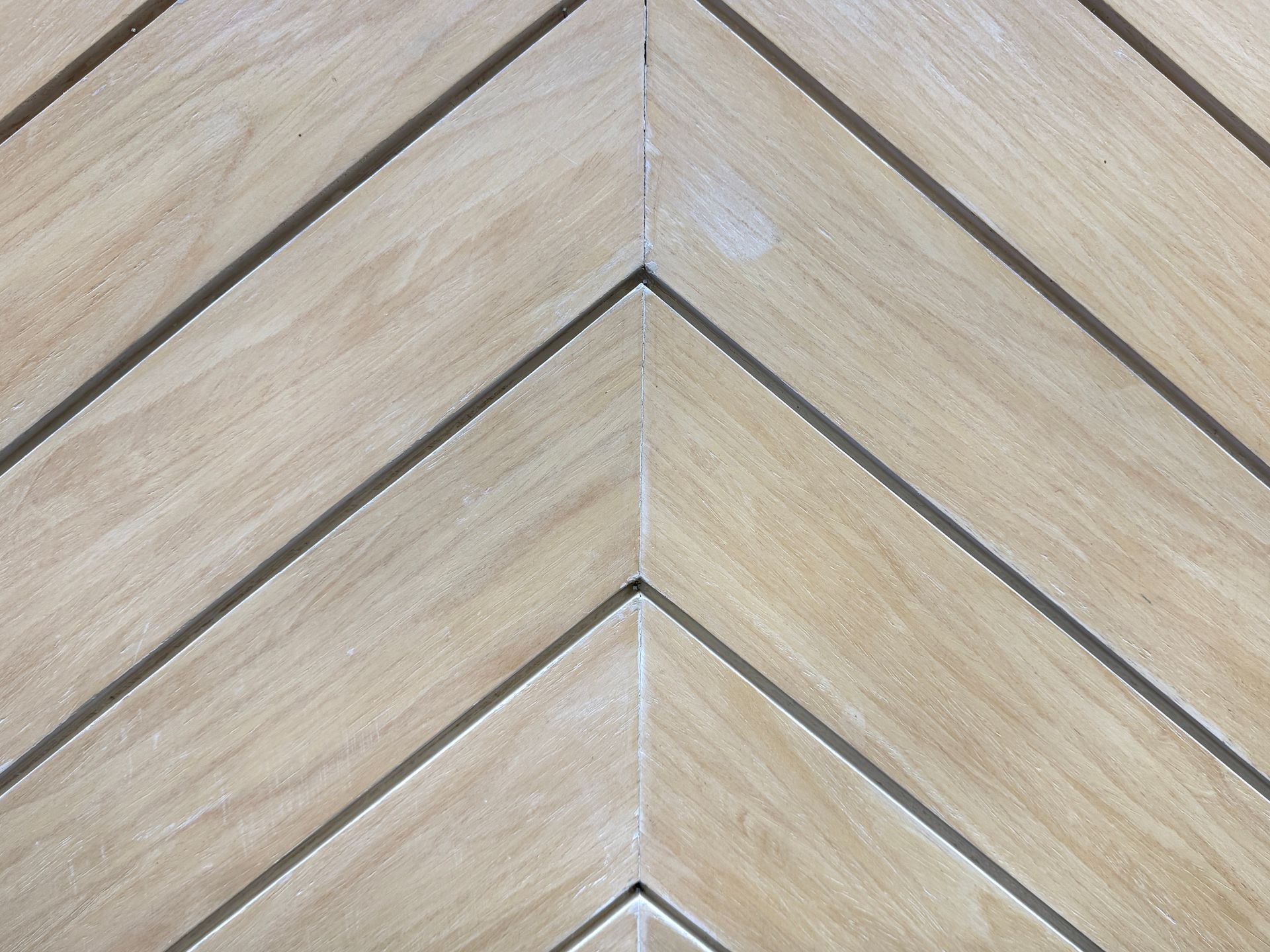 Light wood surface with a chevron pattern, featuring etched lines.