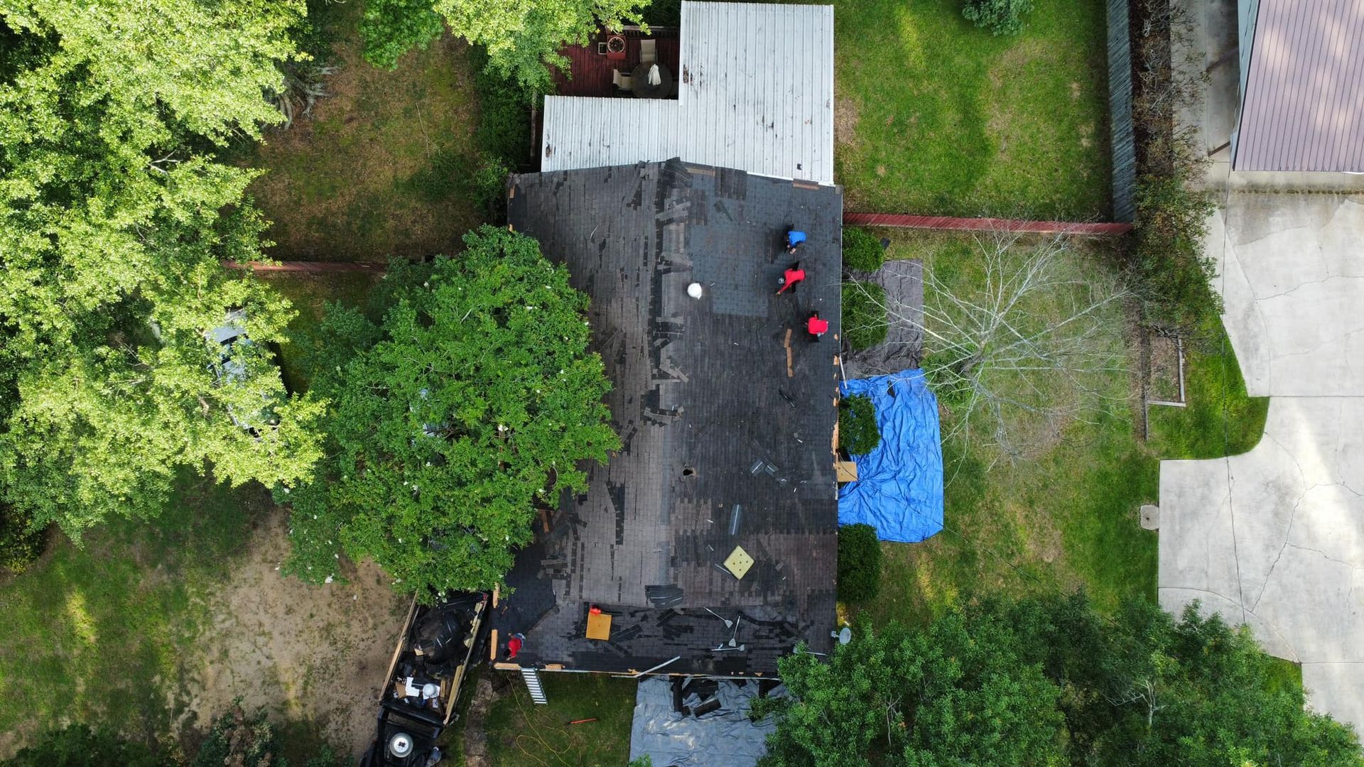 An aerial view of a house with a blue tarp on the roof.