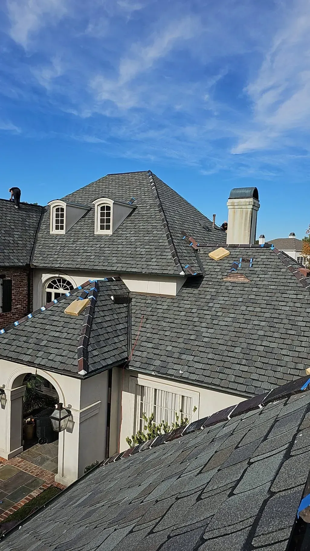 A large house with a gray roof and a blue sky in the background.