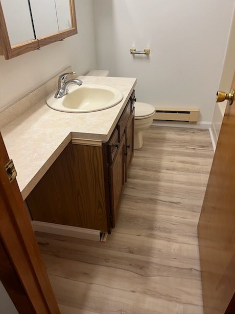 Modern bathroom with wood cabinets, white countertop, large mirror, and glass shower.