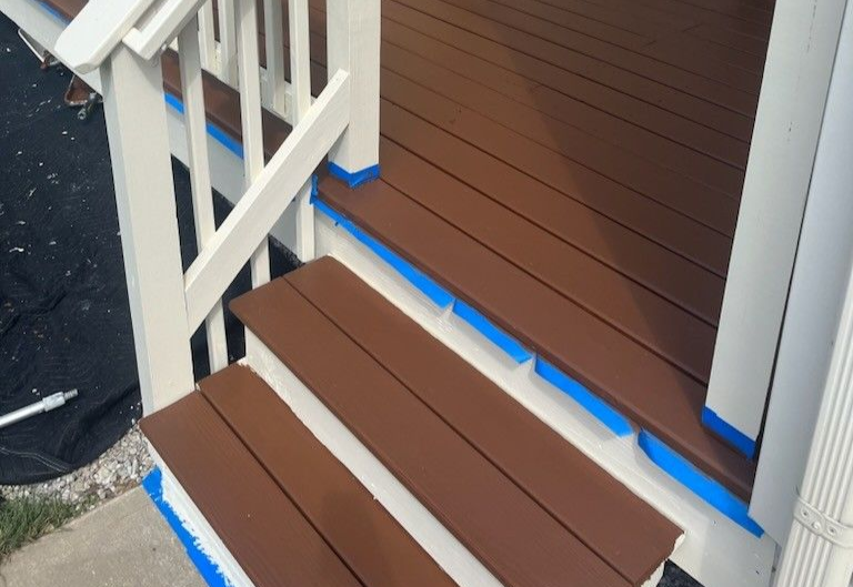Wooden deck with brown railing overlooking trees.