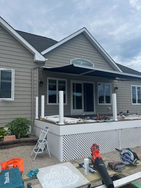 Modern bathroom with black tile walls, wood vanity, white sink, and glass shower.