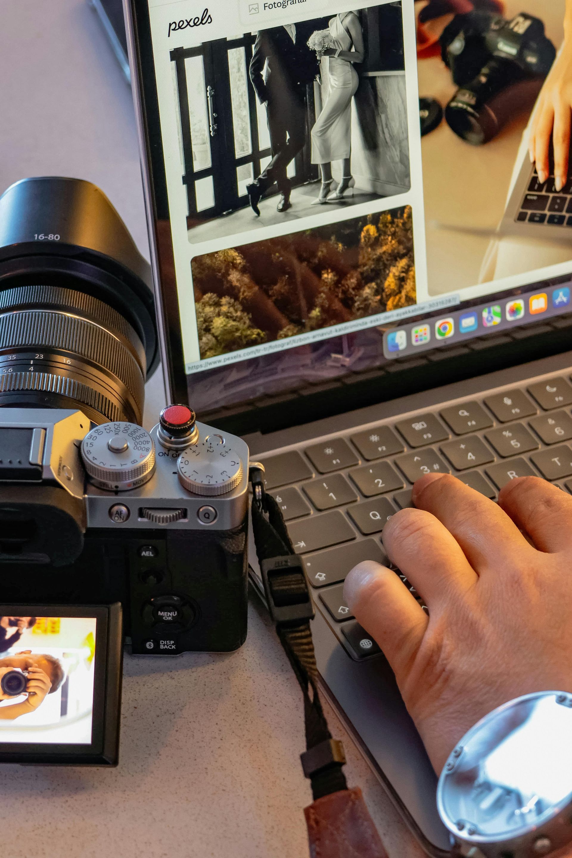 A person is typing on a laptop next to a camera